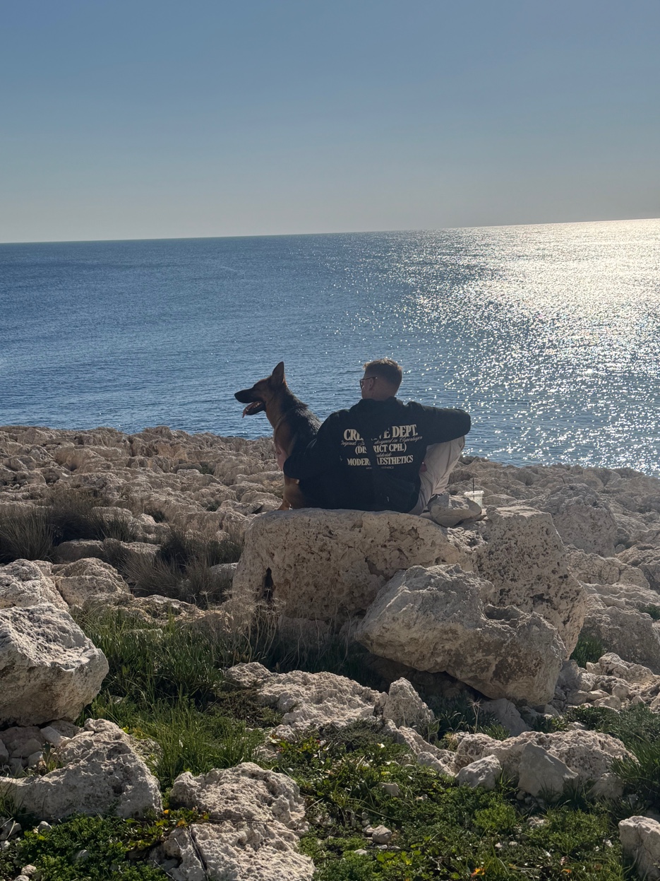 Alex and Roxy sitting on the rocks looking out to sea Cape Greco