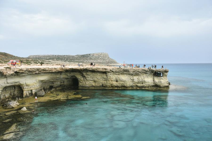 Sea caves at Cape Greco Ayia Napa — limestone cliffs with turquoise water and swimmers below