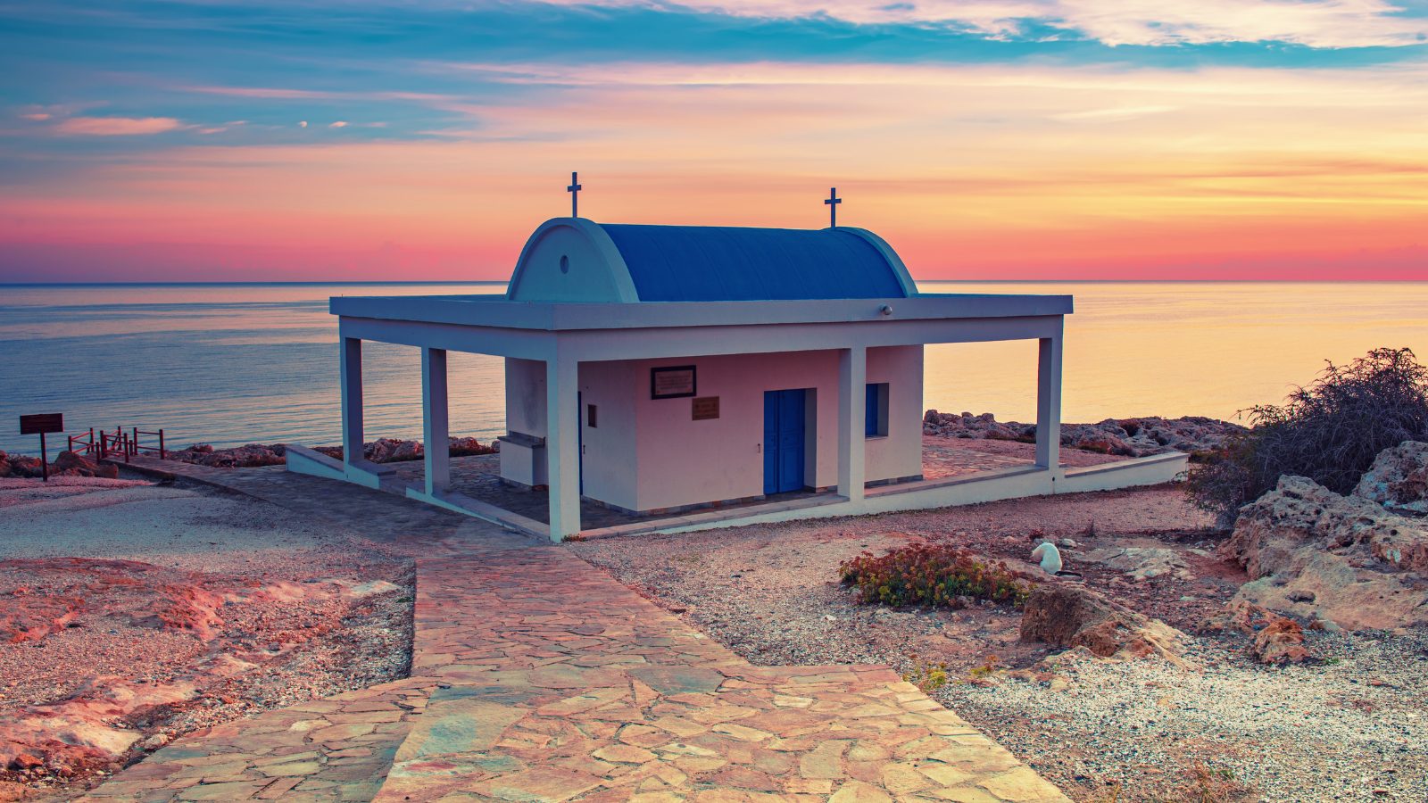 Agioi Anargiri chapel Cape Greco — white chapel with blue dome at sunset by the sea