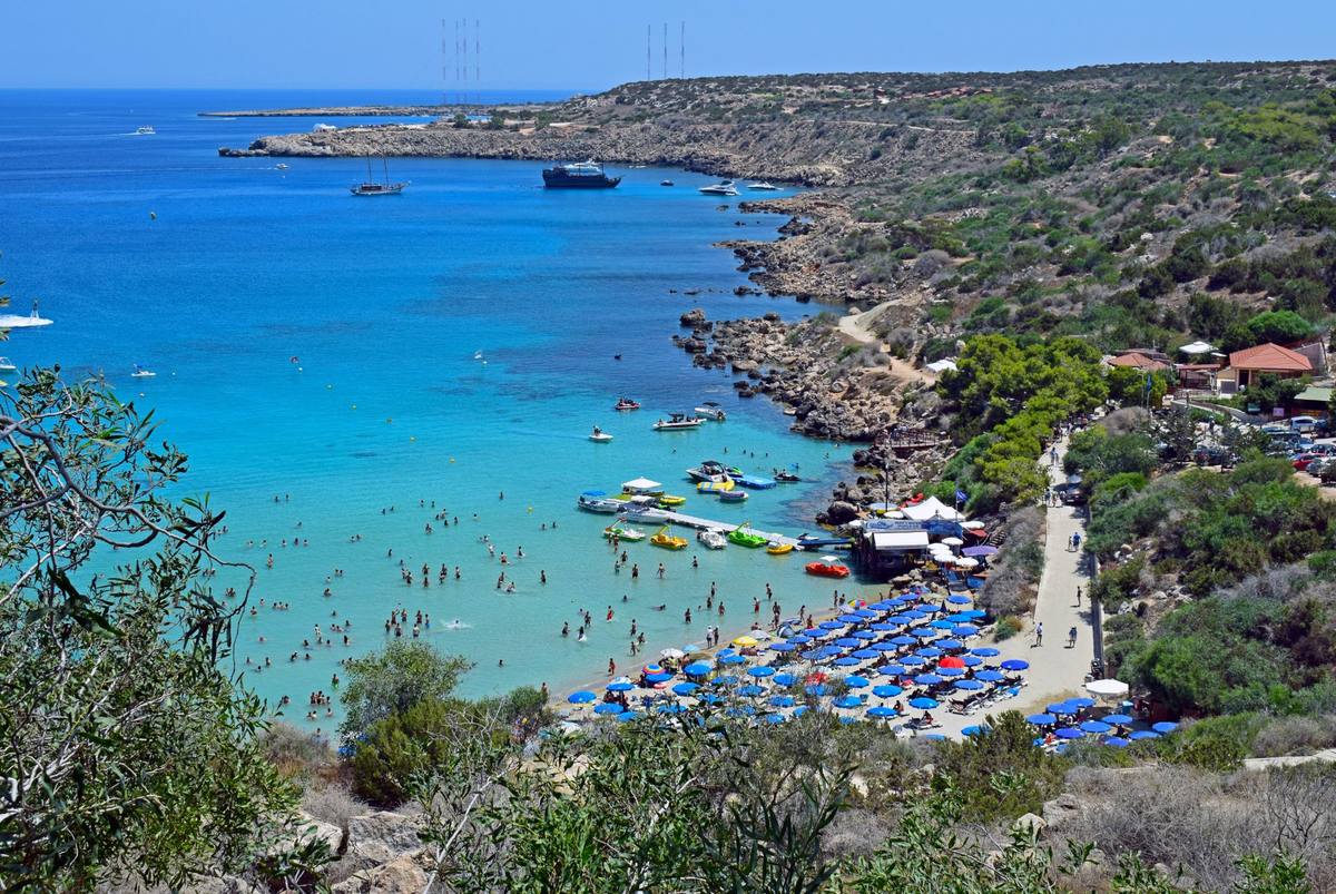 Konnos Bay aerial view Cyprus turquoise water sunbeds boats